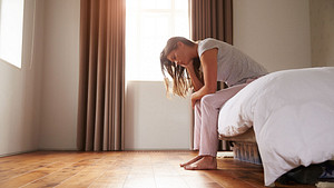 Mujer sentada en la cama que sufre de insomnio y depresión